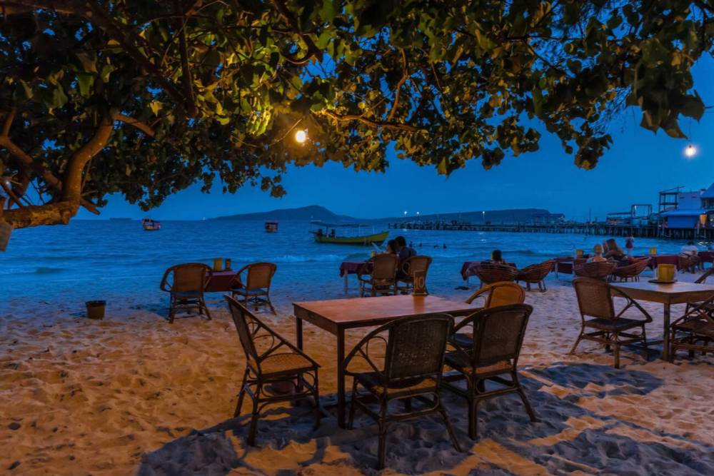 File di sedie in rattan sulla spiaggia di Koh Touch di notte